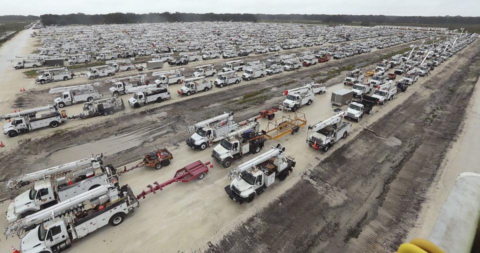 Utility trucks are staged in a rural lot in The Villages of Sumter County, Fla.