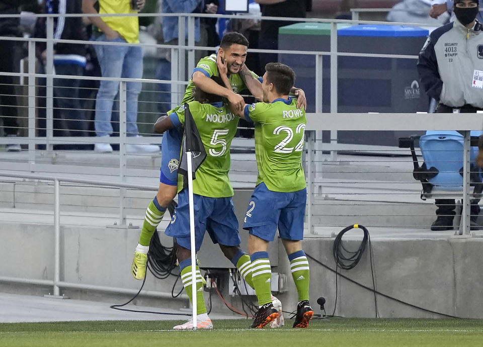 Seattle Sounders midfielder Cristian Roldan, top, celebrates with Nouhou Tolo (5) and Kelyn Rowe (22) after scoring a goal against the San Jose Earthquakes during the first half of an MLS soccer match Wednesday, May 12, 2021, in San Jose, Calif. (AP Photo/Tony Avelar)