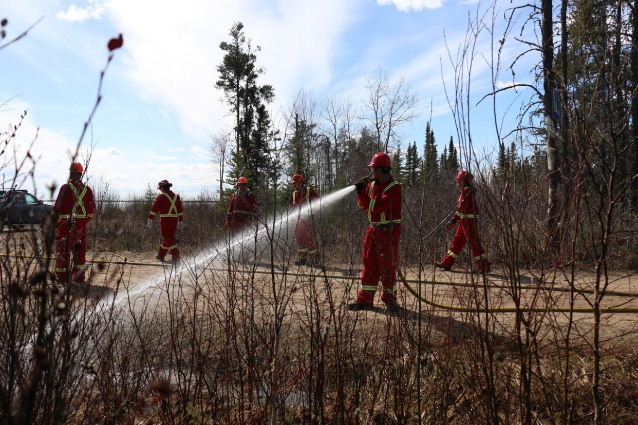 A group of men from around northern Saskatchewan practice using a firehose during firefighting training. (Sam Samson/CBC News - image credit)