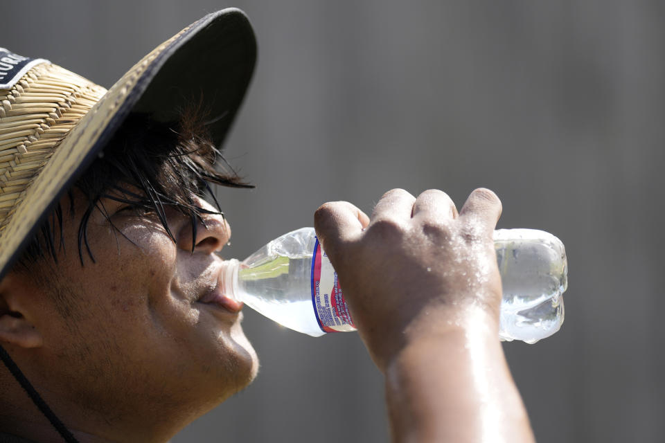 Carlos Rodriguez drinks water while taking a break from digging fence post holes Tuesday, June 27, 2023, in Houston. Meteorologists say scorching temperatures brought on by a heat dome have taxed the Texas power grid and threaten to bring record highs to the state. (AP Photo/David J. Phillip)