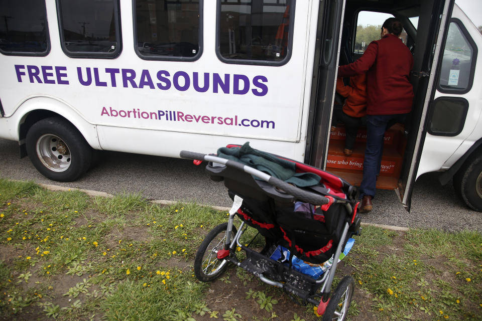 Melanie Wong walks her young son into an ultrasound van on Tuesday, April 12, 2022, outside the Hope Clinic for Women in Granite City, Ill. Wong sometimes comes to stand with other abortion opponents outside the clinic. The van belongs to another abortion opponent who offers ultrasounds to women who've come to the clinic for abortions. The hope is that seeing the ultrasound will persuade them not to have an abortion. (AP Photo/Martha Irvine)