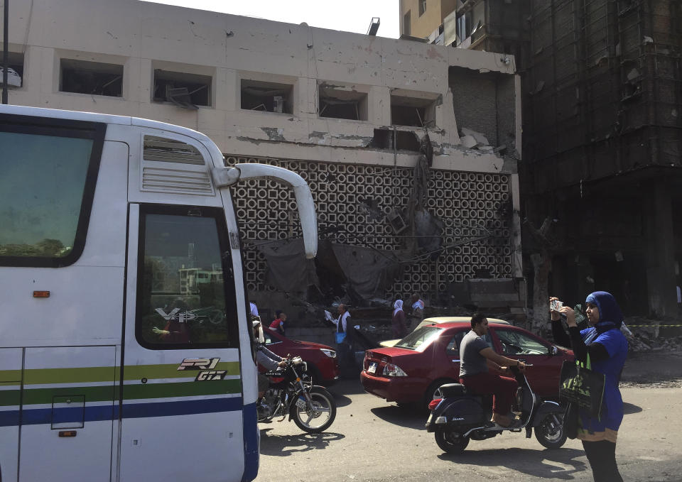 People survey the aftermath of a fiery car crash outside the National Cancer Institute in Cairo, Egypt, Monday, Aug. 5, 2019. The multiple-car crash set off an explosion that ignited a fire at Egypt's main cancer hospital, the government said.(AP Photo/Maya Alleruzzo)