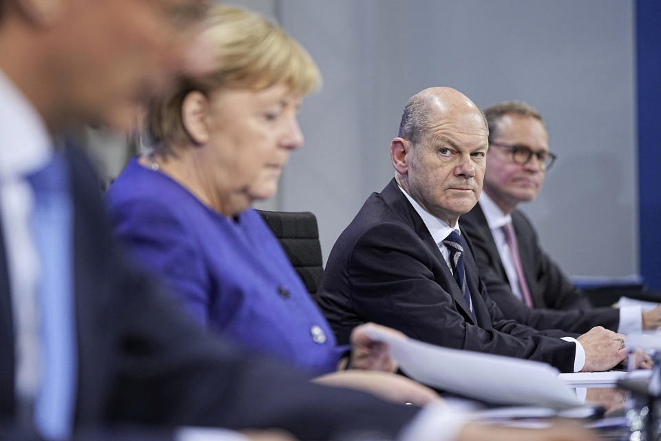 Federal Finance Minister Olaf Scholz, second right, looks at German Chancellor Angela Merkel, during a news conference in Berlin, Thursday, Nov. 18, 2021. German lawmakers have approved new measures to rein in record coronavirus infections after the head of Germany’s disease control agency warned the country could face a “really terrible Christmas.” The measures passed in the Bundestag on Thursday includes requirements for employees to prove they are vaccinated, recovered from COVID-19 or have tested negative for the virus in order to access communal workplaces. (Michael Kappeler, Pool via AP)