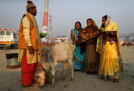 Women devotees pray to a calf after a holy dip at Sangam during Magh mela festival, in Prayagraj, India. Friday, Feb. 19, 2021. Millions of people have joined a 45-day long Hindu bathing festival in this northern Indian city, where devotees take a holy dip at Sangam, the sacred confluence of the rivers Ganga, Yamuna and the mythical Saraswati. Here, they bathe on certain days considered to be auspicious in the belief that they be cleansed of all sins. (AP Photo/Rajesh Kumar Singh)