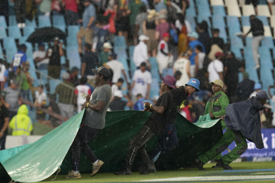 Ground workers pull rain covers as play has been called off due to bad light during the first day of the Test cricket match between South Africa and India, at Centurion Park, in Centurion, South Africa, Tuesday, Dec. 26, 2023. (AP Photo/Themba Hadebe)