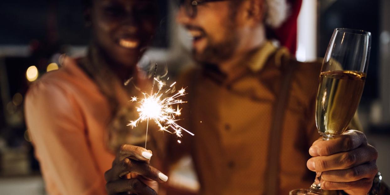 close up of couple celebrating new year and having fun with sparklers while drinking champagne at home