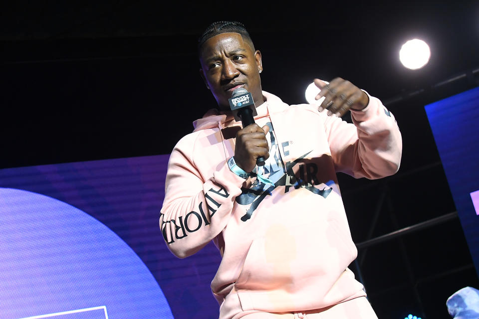 American rapper Yung Joc wearing pink and speaking on stage.