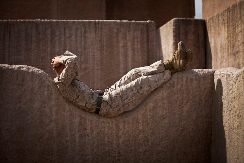 Lance Cpl. Curtis E. Sledge, a machine gunner assigned to Weapons Platoon, Alpha Company, 1st Battalion, 3rd Marine Regiment, relaxes on a rock wall prior to participating in a night raid aboard Marine Corps Training Area Bellows, April 17, 2015.
