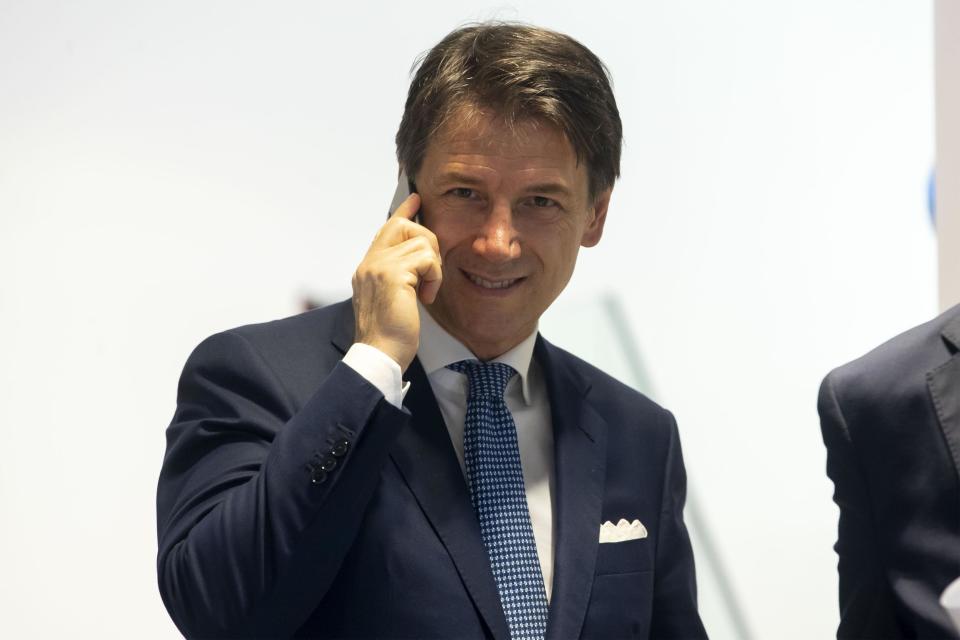 Italy's Prime Minister, Giuseppe Conte, talks at the phone inside a mobile phones shop in the center of Rome, Tuesday, Aug. 27, 2019. While Italians don't know if they'll soon have a new government, let alone who would lead it, U.S. President Donald Trump has cast his vote -- for caretaker Premier Giuseppe Conte. A day after the two finished attending the G-7 summit in France, Trump tweeted on Tuesday that he hoped Conte would "remain" as premier. (Massimo Percossi/ANSA via AP)