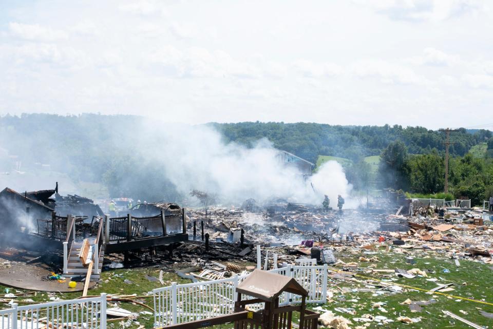 Two firefighters stand on the debris around the smoldering wreckage of the the three houses that exploded near Rustic Ridge Drive and Brookside Drive in Plum, Pa., on Saturday.