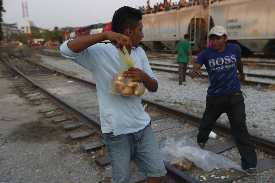 A Central American migrant holds his bag of bread away from another migrant, who attempts to take it away from him, before climbing on a north-bound freight train during his journey toward the US-Mexico border, in Ixtepec, Oaxaca state, Mexico, Tuesday, April 23, 2019. Just like increased U.S. border protection, Mexico's increased enforcement efforts push migrants into using more dangerous means of travel, like the freight trains running north known to them as "La Bestia". (AP Photo/Moises Castillo)