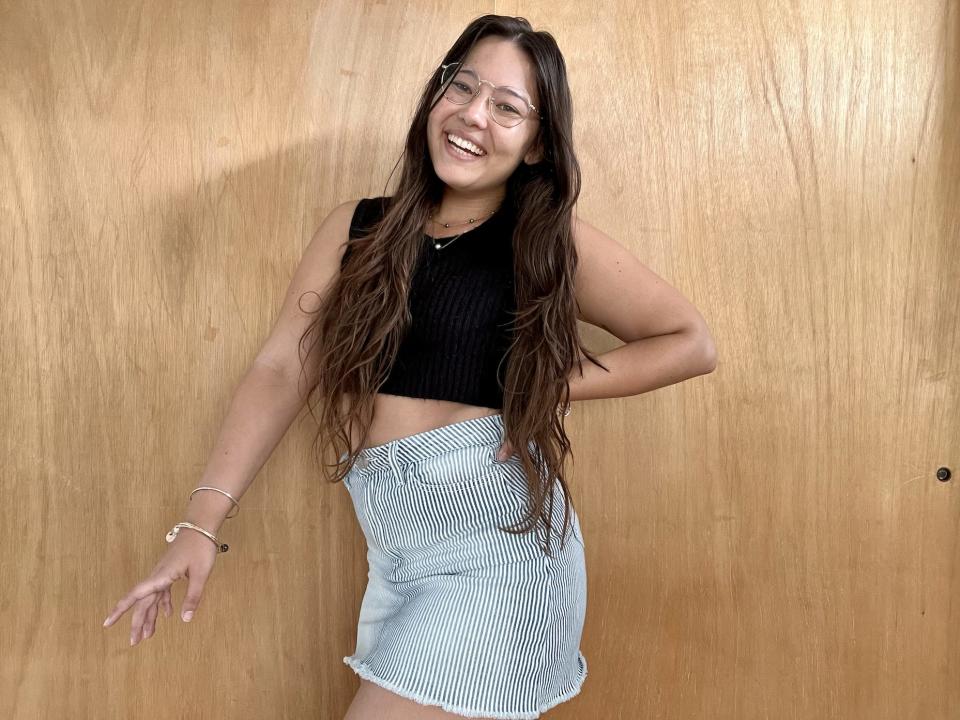 Ashley posing while wearing a black crop top and a jean skirt