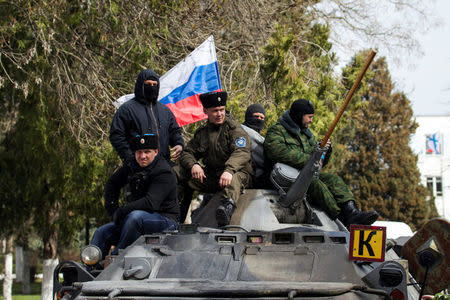FILE PHOTO: A man (C) with the insignia of the Russian state-registered Cossack society and other pro-Russian supporters sit on top of a Ukrainian APC after breaking into the territory of the naval headquarters in Sevastopol, March 19, 2014. REUTERS/Baz Ratner/File Photo