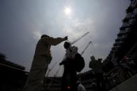 Workers and media memebers are seen under the light of the sun during a heat wave, at the construction site of the New National Stadium, the main stadium of Tokyo 2020 Olympics and Paralympics, during a media opportunity in Tokyo, Japan July 18, 2018. REUTERS/Issei Kato