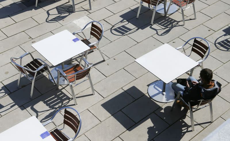 A customer waits to be served in an open terrace bar seen next to Palma de Mallorca's cathedral