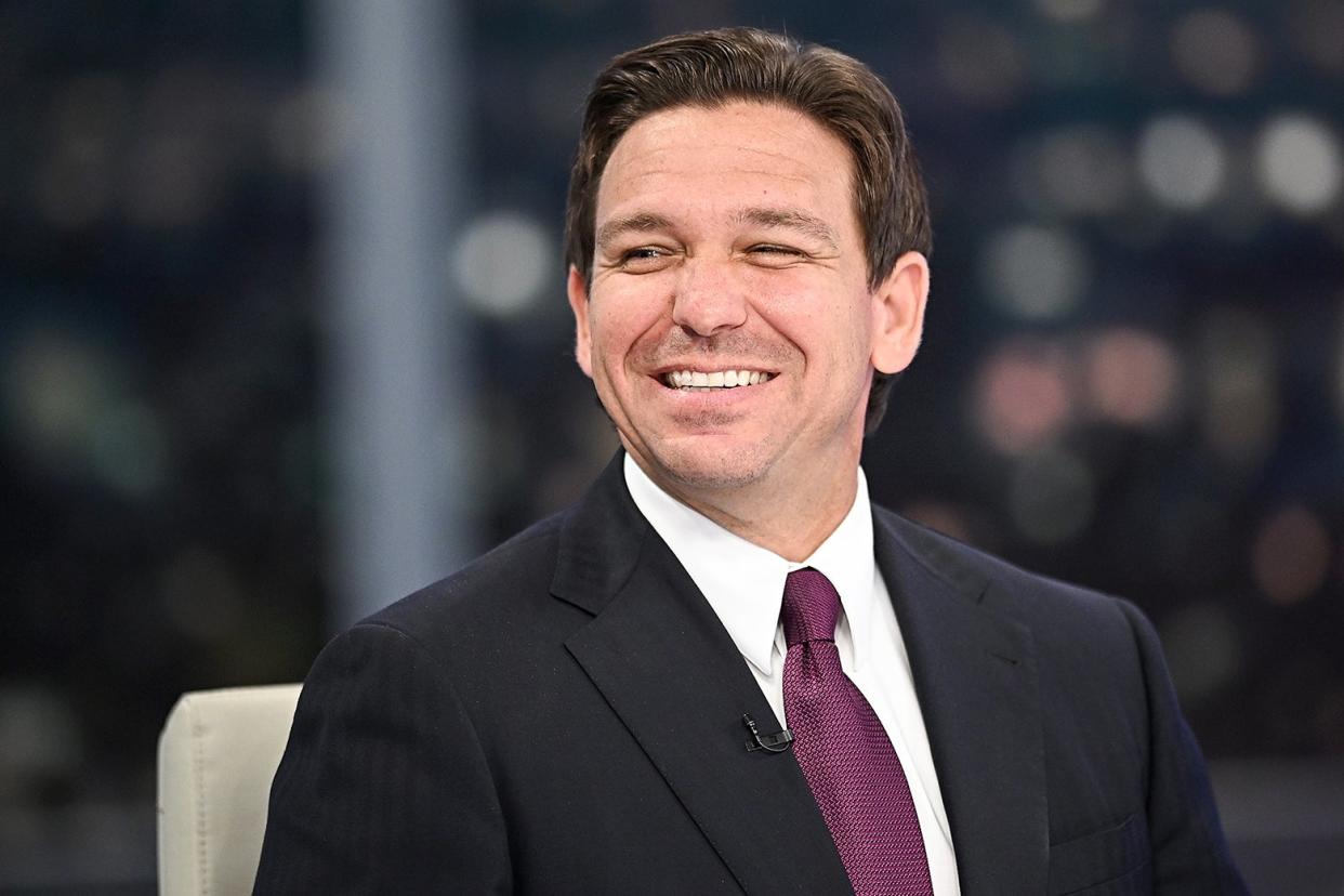 DeSantis has swoopy hair and a big wooden smile.