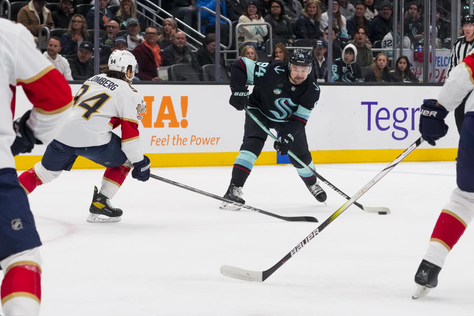 Seattle Kraken center Devin Shore, center, looks to shoot against Florida Panthers left wing Ryan Lomberg, left, during the first period of an NHL hockey game Tuesday, Dec. 12, 2023, in Seattle. (AP Photo/Lindsey Wasson)