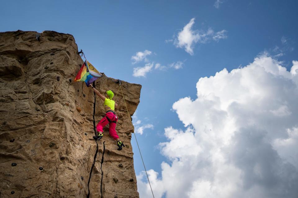 Drag queen Anaslaysia, Brit Bordner, reaches for the LGBTQ+ flag to finish her climb at the Audubon Climbing Wall, hosted Queer Climbing Columbus.