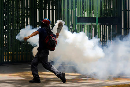 A demonstrator throws a tear gas canister during the 'march of the empty pots' against Venezuelan President Nicolas Maduro's government in Caracas, Venezuela, June 3, 2017. REUTERS/Carlos Garcia Rawlins