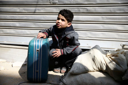 A boy holds a suitcase during evacuation from the besieged town of Douma, Eastern Ghouta, in Damascus, Syria, March 13. REUTERS/Bassam Khabieh