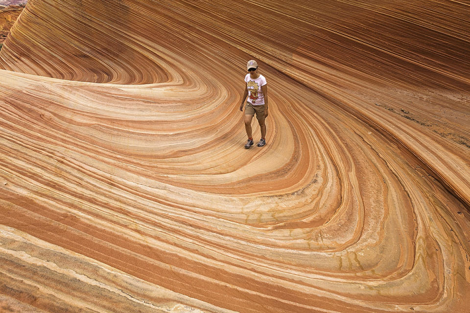 <p>A woman is seen wandering through the natural sandstone known as "The Wave," which forms a swirl-like design, in Arizona.</p>