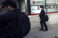 Men walk past an electronic stock board showing Japan's Nikkei 225 index at a securities firm Wednesday, April 8, 2020, in Tokyo. Asian shares were mostly lower after gyrating in early trading amid uncertainty over the coronavirus outbreak. Japan’s Nikkei 225 inched up in Wednesday morning trading, but benchmarks in Australia, South Korea and Chine are lower. (AP Photo/Eugene Hoshiko)