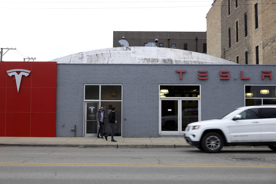 People exit a Tesla Motor showroom in Chicago on Wednesday, March 31, 2021. President Joe Biden outlined a huge $2.3 trillion plan Wednesday to reengineer the nation’s infrastructure in what he billed as “a once in a generation investment in America” that would undo his predecessor’s signature legislative achievement of giant tax cuts for corporations in the process. (AP Photo/Shafkat Anowar)