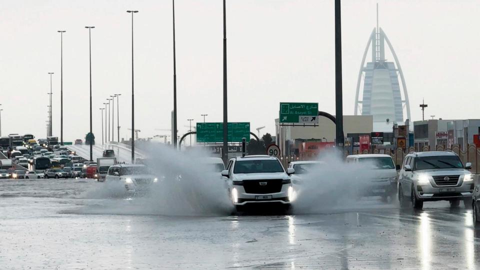 PHOTO: An SUV splashes through standing water on a road with the Burj Al Arab luxury hotel seen in the background in Dubai, United Arab Emirates, April 16, 2024.  (Jon Gambrell/AP)
