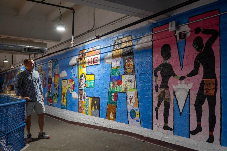 Developer Kelley Hrabe looks over the murals that cover the walls around the elevated walking track in the gymnasium at Y Lofts.