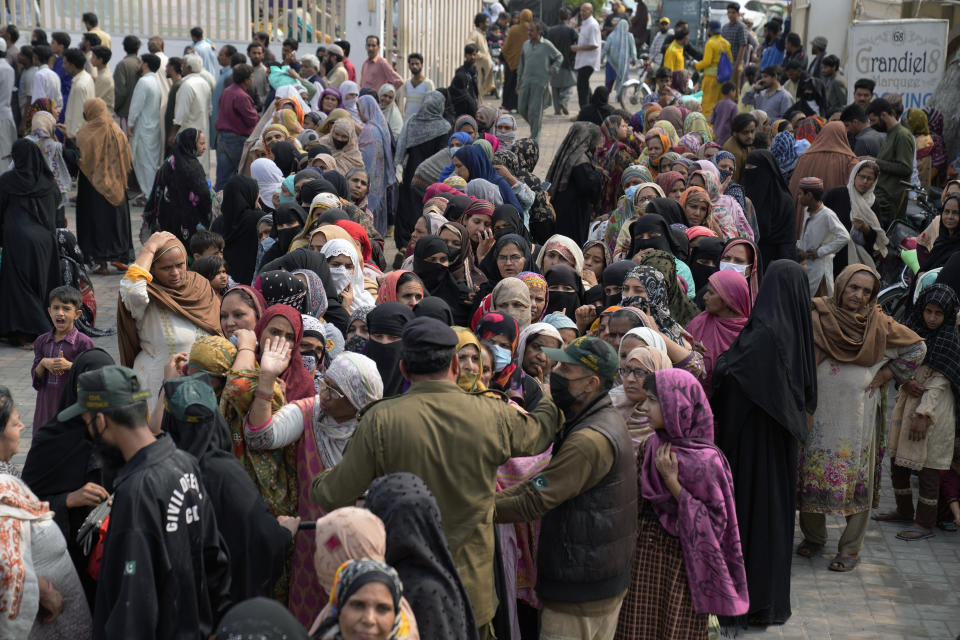 Police officers control a crowd gathered to get a free sack of wheat flour at a distributing point, in Lahore, Pakistan, Monday, March 20, 2023. Pakistan's Prime Minister Shahbaz Sharif will provide free flour to deserving and poor families during the Muslim's holy month of Ramadan due to high inflation in the country. (AP Photo/K.M. Chaudary)