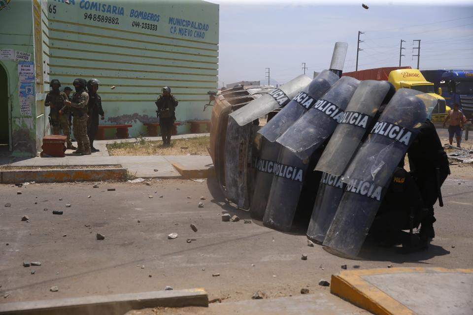 Riot police create a shield wall during clashes with supporters of ousted Peruvian President Pedro Castillo on the Pan-American North Highway, in Chao, Peru, Thursday, Dec. 15, 2022. Peru's new government declared a 30-day national emergency on Wednesday amid violent protests following Castillo's ouster, suspending the rights of "personal security and freedom" across the Andean nation. (AP Photo/Hugo Curotto)