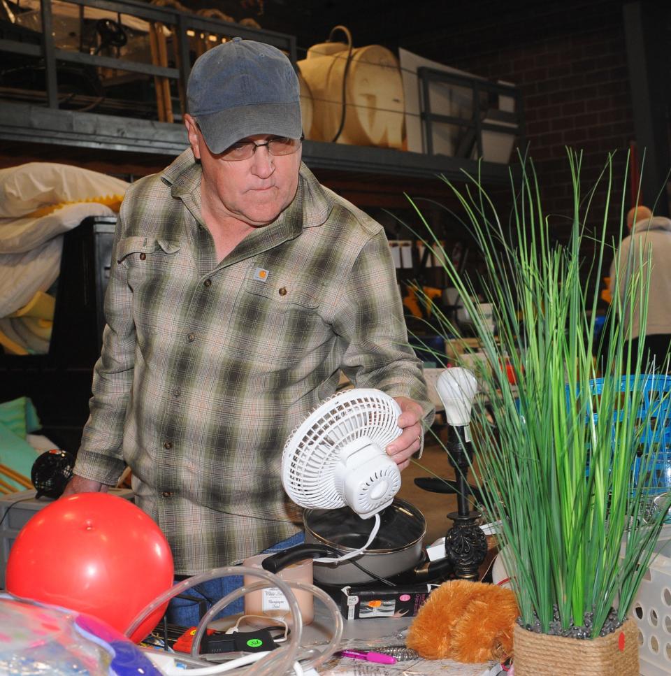 Brian Myers inspects a fan available for sale Thursday, May 19, 2022, during the annual "Trash to Treasure" sale at the University of Mount Union Physical Plant.
