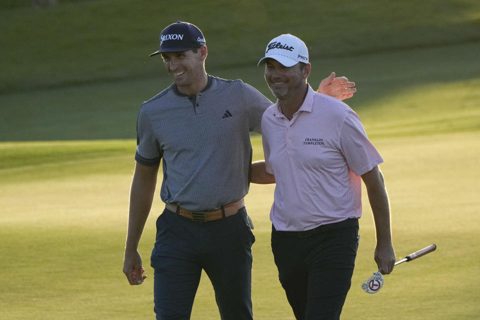 Brandon Matthews, left, greets teammate Sean O'Hair as they walk off the 17th green during the first round of the PGA Zurich Classic golf tournament at TPC Louisiana in Avondale, La., Thursday, April 20, 2023. (AP Photo/Gerald Herbert)