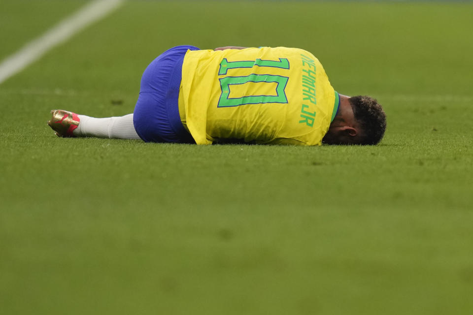 Brazil's Neymar, center, lies on the pitch during the World Cup group G soccer match between Brazil and Serbia, at the Lusail Stadium in Lusail, Qatar, Thursday, Nov. 24, 2022. (AP Photo/Aijaz Rahi)