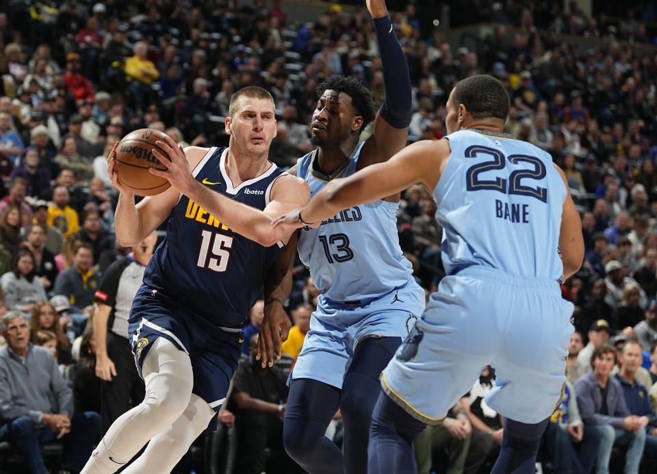 Denver Nuggets center Nikola Jokic, left, drives past Memphis Grizzlies forward Jaren Jackson Jr., back right, and guard Desmond Bane in the first half of an NBA basketball game Monday, March 25, 2024, in Denver. (AP Photo/David Zalubowski)