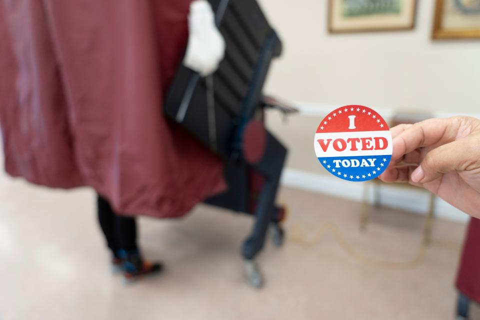 Eva Hermano, a poll worker, waits for a voter to exit the voting booth to give him a "I Voted Today" sticker at the Civic Center in Hackensack, N.J. on Tuesday Nov. 8, 2022. 