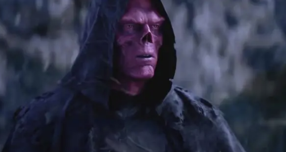 Red Skull from the Marvel Cinematic Universe stands in a dark, eerie environment wearing a hooded cloak