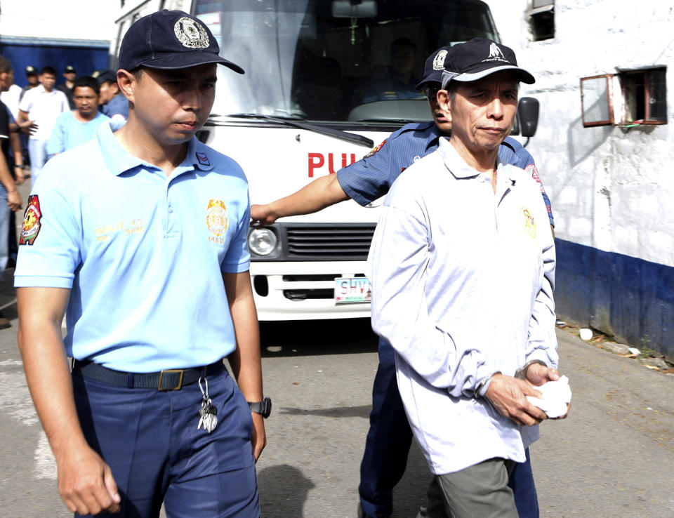 In this photo released by the Philippine National Police Public Information Office, suspected communist leader, Benito Tiamzon, right, is escorted as he arrives at Camp Crame police headquarters in suburban Quezon city, north of Manila, Philippines on Sunday March 23, 2014. Philippine officials said Sunday that they would not release two leaders of a violent rebel group fighting to overthrow the government, whose arrests were a serious blow to one of Asia's longest-running communist insurgencies. (AP Photo/Philippine National Police, Public Information Office)