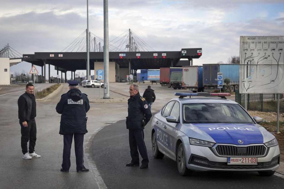 Kosovo police officers inform travelers of the closed Merdare border crossing between Kosovo and Serbia on Wednesday, Dec. 28, 2022. Kosovo closed the border crossing in Merdare, following an erected barricade by Serb protesters inside Serbia late Tuesday night, the third official border crossing closed this month following rising tensions between Kosovo and Serbia. (AP Photo/Visar Kryeziu)
