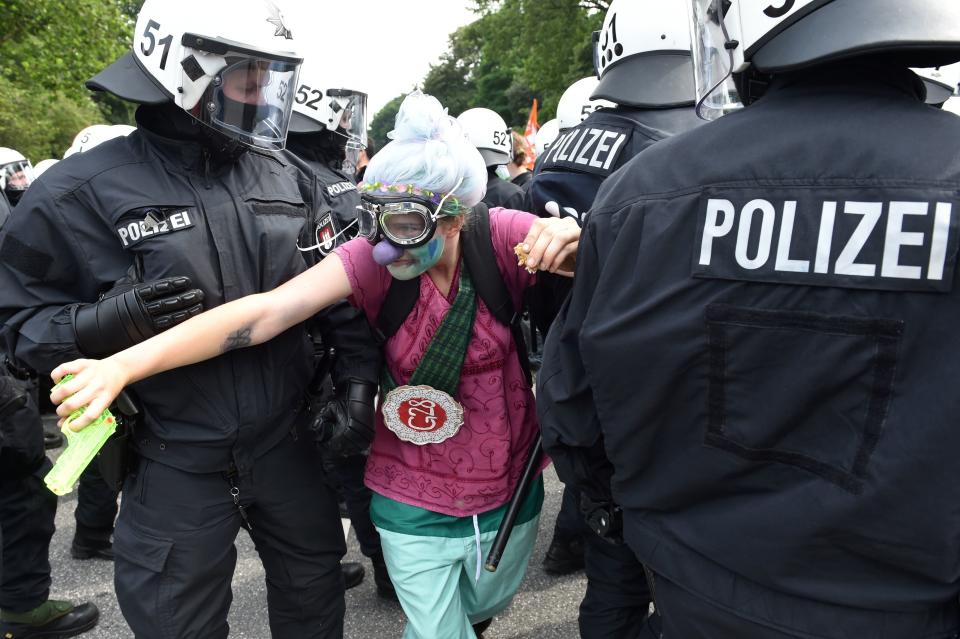 Policemen lead away a demonstrator dressed as a clown.&nbsp;