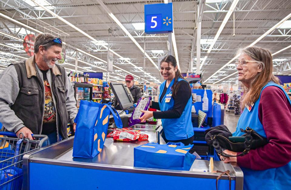 Terry White shares a laugh with Walmart employees Jaqueline Lazaro and Linda Holstrom at a checkout station at a Walmart in Loveland on Oct. 13.
