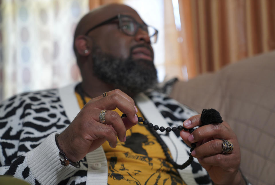 Lama Rod Owens holds his Buddhist mala beads made of lava rock used for prayer and meditation while at his childhood home in Rome, Georgia on Saturday, March 30, 2024. Owens, a self-proclaimed Black Buddhist Southern Queen, grew up Christian and was raised by his Methodist minister mother. Today, he is an influential voice in a new generation of Buddhist teachers, respected for his work focused on social change, identity and spiritual wellness. (AP Photo/Jessie Wardarski)