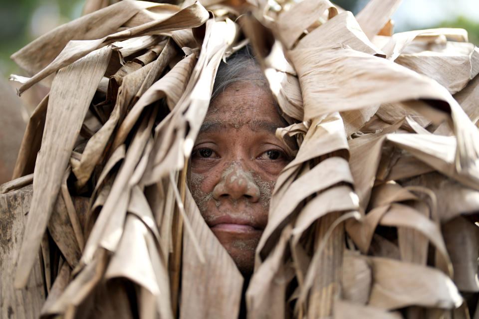 A devout Catholic, dressed in dried banana leaves, participates in mass during the mud festival at the church of Saint John the Baptist at Bibiclat, Nueva Ecija province, northern Philippines, Monday, June 24, 2024. (AP Photo/Aaron Favila)