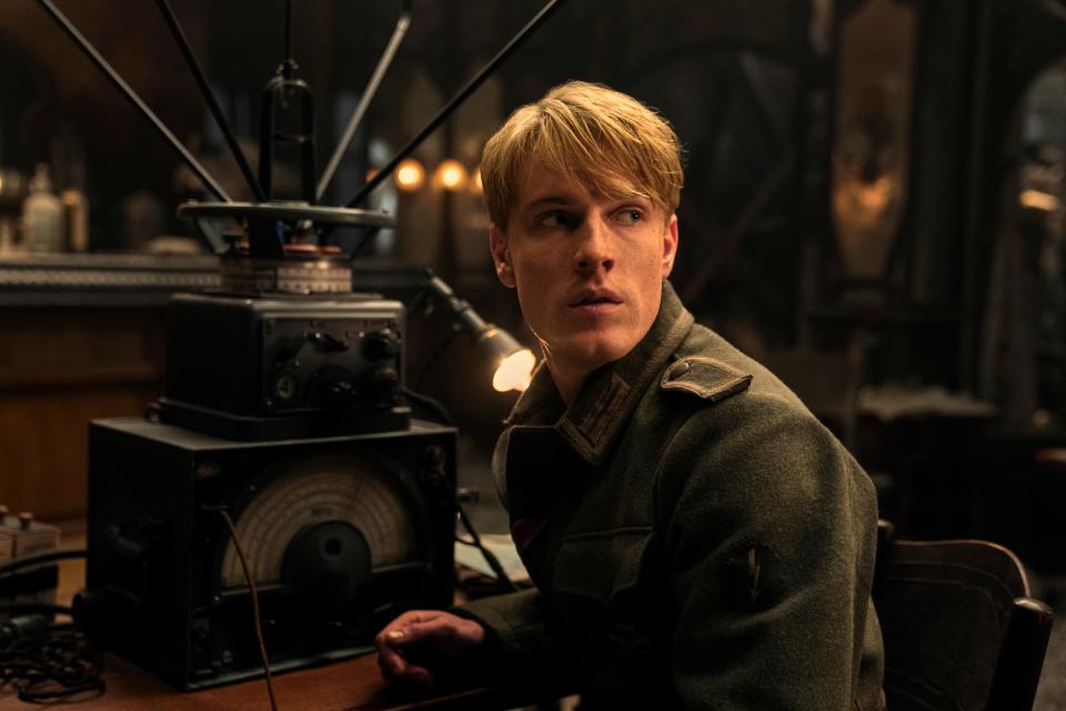 louis hofmann as werner in all the light we cannot see. he's a young man in a german military uniform, sitting in front of an old radio
