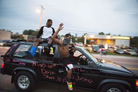 Protesters hang out of a car as they honk their horn and chant during ongoing demonstrations in reaction to the shooting of Michael Brown in Ferguson, Missouri August 16, 2014. REUTERS/Lucas Jackson
