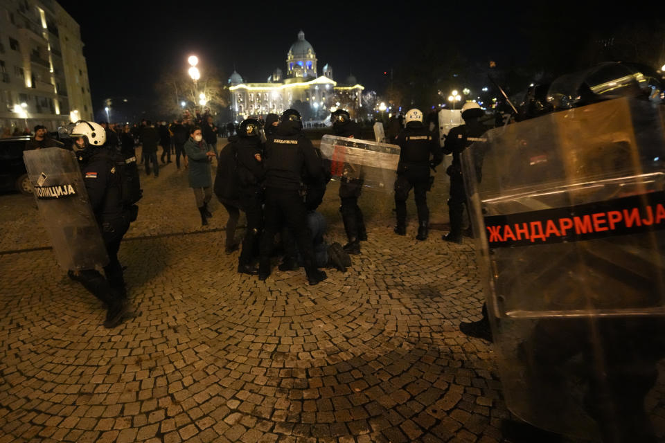 Protesters clash with gendarme in Belgrade, Serbia, Sunday, Dec. 24, 2023. Police in Serbia have fired tear gas to prevent hundreds of opposition supporters from entering the capital's city council building to protest what election observers said were widespread vote irregularities during a general election a week ago. (AP Photo/Darko Vojinovic)