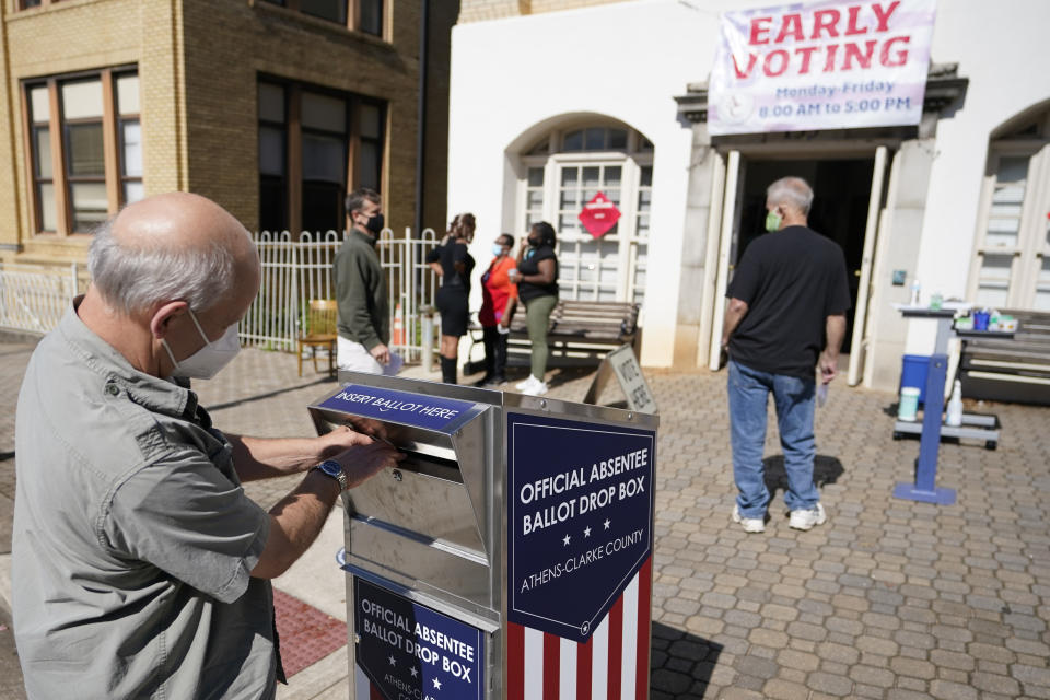 FILE - In this Monday, Oct. 19, 2020 file photo, a voter submits a ballot in an official drop box during early voting in Athens, Ga. Ballot drop boxes were enormously popular during the 2020 election, with few problems reported. Yet they have drawn the attention of Republican lawmakers in key states who say security concerns warrant new restrictions. (AP Photo/John Bazemore, File)