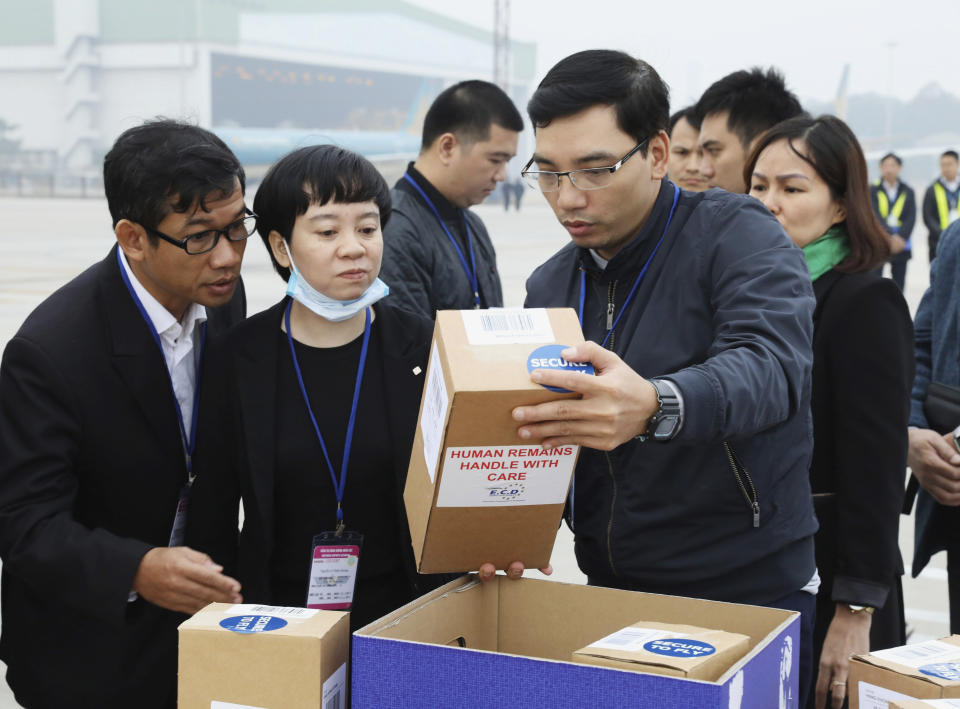 Vietnamese officials examine a carton box with human remains at the tarmac of the Noi Bai airport in Hanoi, Vietnam, Saturday, Nov. 30, 2019. The last remains of the 39 Vietnamese who died while being smuggled in a truck to England last month have been repatriated to their home country. (Lam Khanh/VNA via AP)