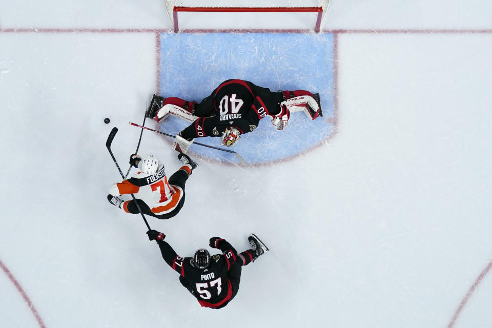 Philadelphia Flyers' Tyson Foerster (71) tries to get a shot past Ottawa Senators' Mads Sogaard (40) as Shane Pinto (57) defends during the second period of an NHL hockey game, Saturday, March 2, 2024, in Philadelphia. (AP Photo/Matt Slocum)