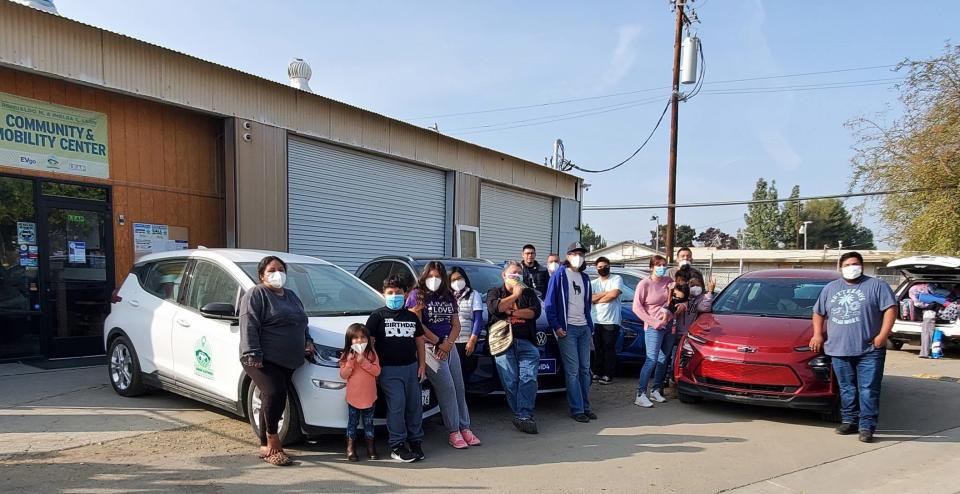 Members of farmworker families and Huron, California, Mayor Rey Léon prepare to go on a weekend camping trip using electric vehicles from the city's Green Raiteros program. During the week, residents use them for medical appointments and other needs.